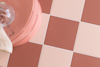 Bruna och vita fyrkantiga kakelplattor i ett schackmönster med en rosa rund kant upptill.