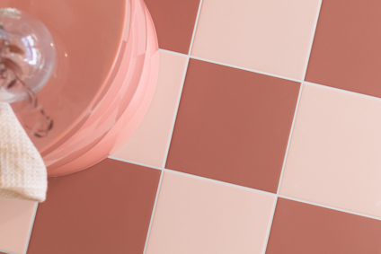 Bruna och vita fyrkantiga kakelplattor i ett schackmönster med en rosa rund kant upptill.