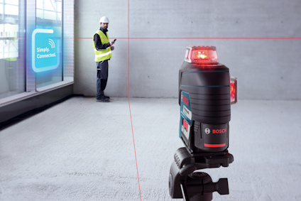 En arbetare med gul väst använder en enhet vid en vägg. En Bosch laseravsändare projicerar röda linjer.
