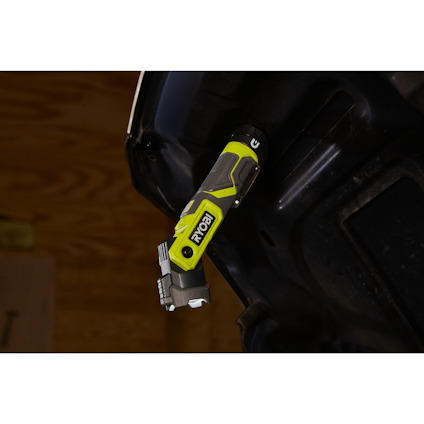 Grön och svart batteridriven verktyg med märket "Ryobi", monterad på en svart yta.