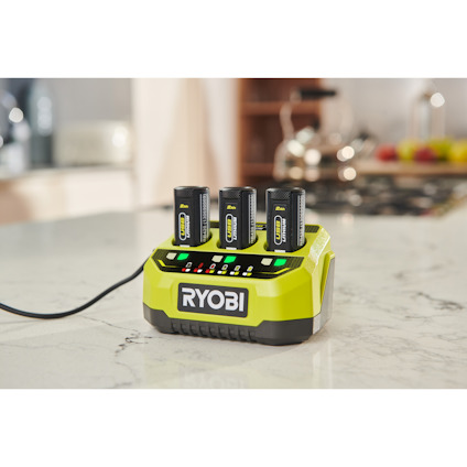 Multiladddare för tre 4V batterier, med texten "RYOBI", på en marmorbänkskiva.