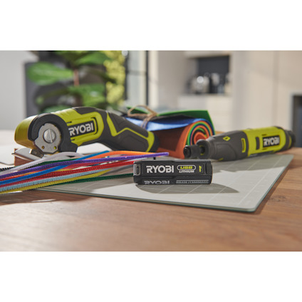 Elektriska verktyg och färgglada remsor ligger på ett bord, med en RYOBI USB Lithium-batteri i förgrunden.