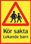 Treskylts varning "Kör sakta, Lekande barn" med röd triangel och silhuetter av barn. Gul bakgrund.