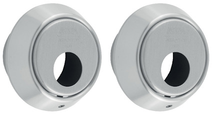 Två cylinderbehör i metall med cirkulära öppningar och text "ASSA" ingraverat överst.