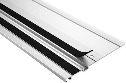 Aluminiumprofil med svart häftande remsa och flexibel kant på en slät yta.