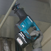 En person använder en Makita batteridriven tigersåg för att såga i ett metallrör.