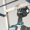 En borrmaskin från Makita är placerad vid sidan av en aluminiumstege.