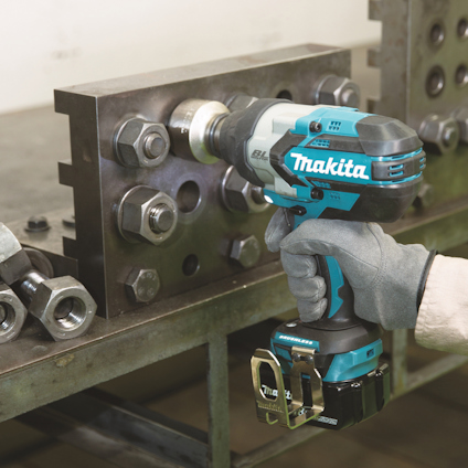 Sladdlös Makita borrmaskin i användning vid metallarbete, handskbeklädd hand håller verktyget.
