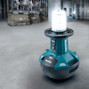 Portabel arbetslampa i en industriell miljö, ljussken, märkning "Makita". Plattform och utrustning i bakgrunden.