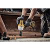 En person i arbetshandskar använder en DeWalt-borrmaskin för att borra i metall. Andra borrdelar är synliga i förgrunden.