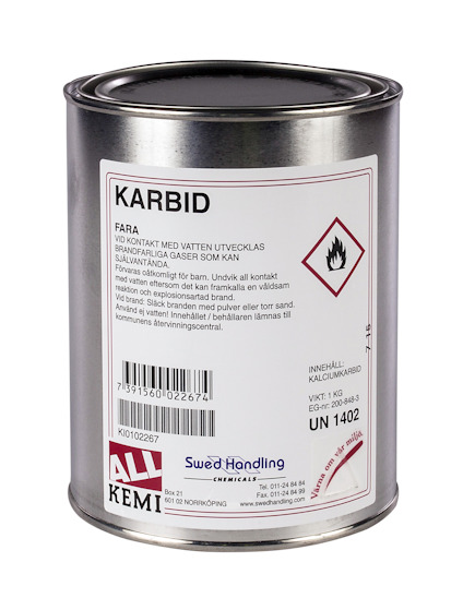 Rund metallburk med etikett som visar texten "KARBID" och varningssymbol för brandfarliga gaser.