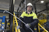 Man i skyddsutrustning med stång, industriell miljö, säkerhetsskydd runt arbetsområde.