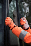 Person i orange arbetskläder och handskar öppnar en dörr i regn.