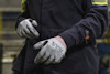 Person with grey work gloves and dark clothing in an industrial setting.