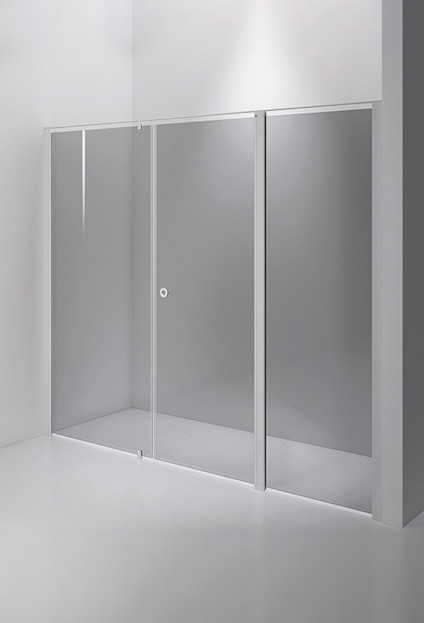 Duschvägg med vit ram och tre sektioner av klart glas, placerad i ett ljust och minimalistiskt badrum.