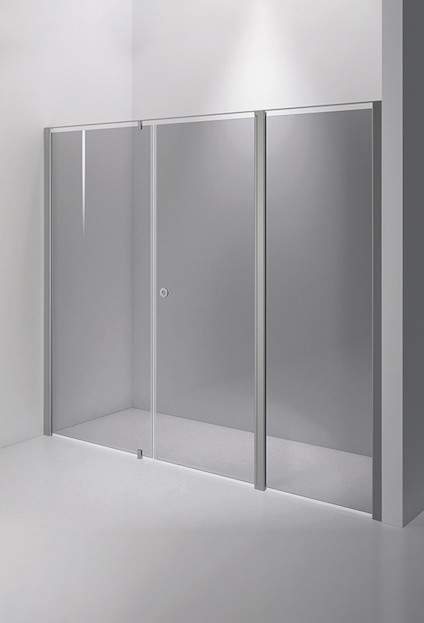 Duschvägg med tre paneler i rökfärgat glas och borstad metallram, monterad i ett hörn av ett vitt badrum.
