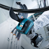 Person använder en Makita-batteridriven kabelsax hållandes i ett grovt material.