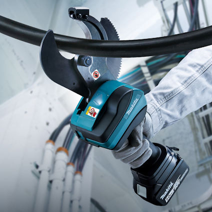 Person använder en Makita-batteridriven kabelsax hållandes i ett grovt material.