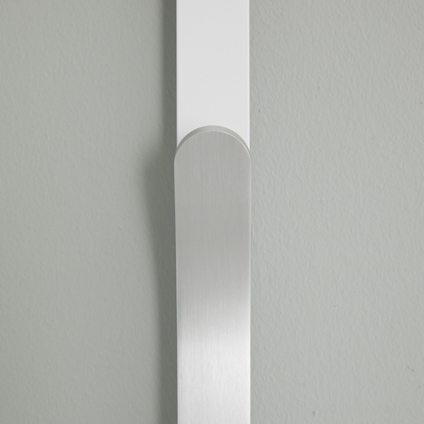 Vit och silverfärgad minimalistisk väggkrok på en grå vägg.