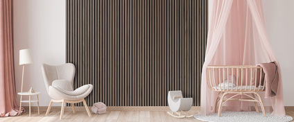 Ett rum med rosa gardiner, beige stol, randigt väggpanel och en spjälsäng med rosa sänghimmel.