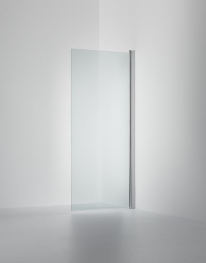 Transparent duschvägg i glas med en polerad metallprofil, placerad mot hörnet av ett vitt rum.