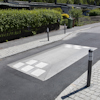 Farthinder i asfalt på en villagata omgiven av häckar och trottoarer med kantsten.