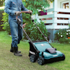 Person i jeanskläder klipper gräsmatta med en blå och svart gräsklippare från Makita.