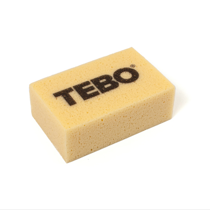 Rektangulär, gul svamp med texten "TEBO" tryckt i svart på ovansidan.