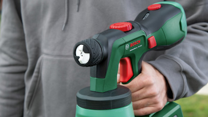 En person håller i en grön Bosch elektrisk sprutpistol.