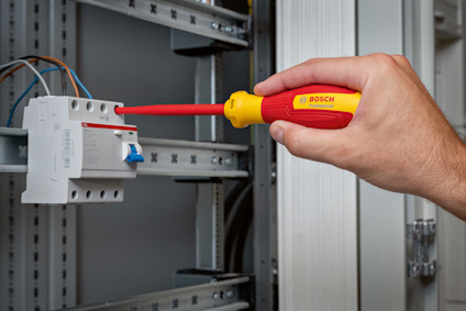 Hand som använder en Bosch-skruvmejsel för att arbeta med en elektrisk panel.
