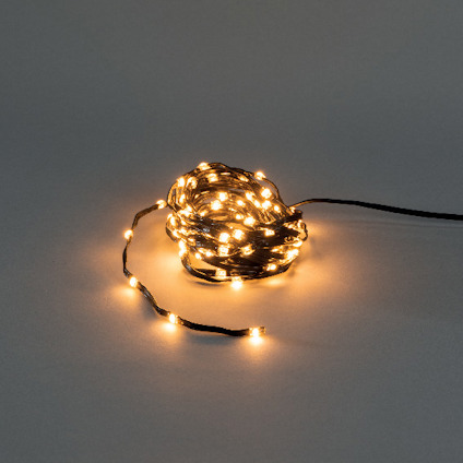 Bunt av amberfärgade LED-lampor på en slinga, liggande på grå yta.