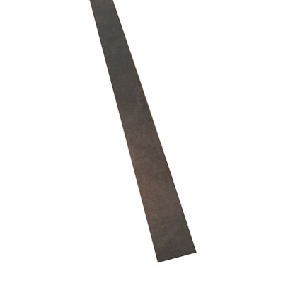 Lång list i mörkt material mot ljus bakgrund, fotograferad diagonalt.