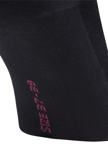 Svart textilmaterial med rosa text längs sidan; texten är delvis synlig med vertikala bokstäver.