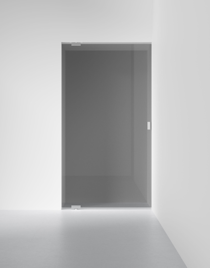 Klarglasdörr installerad i en vit vägg i ett minimalistiskt rum.