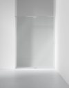 Glasvägg med metallram monterad mellan två vita väggar i ett minimalistiskt rum.