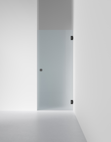 Glasdörr med frostat parti, svarta gångjärn och minimal dörrknopp, installerad i ett modernt vitt rum.
