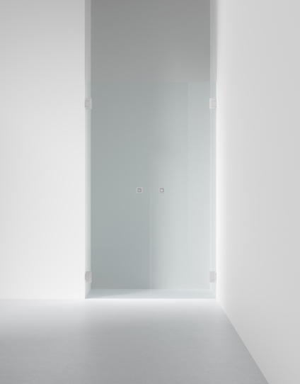 Frostat glasparti med två dörrar och metallhandtag, monterat mellan vita väggar i en minimalistisk interiör.