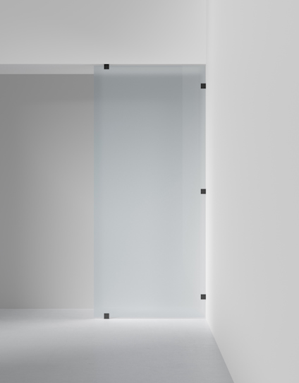 Frostad skjutdörr av glas monterad på en vit vägg med svarta metallfästen.