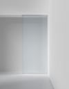 Frostad glasskjutdörr inramad av vita väggar i en minimalistisk interiör.