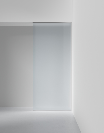 Frostad glasskjutdörr inramad av vita väggar i en minimalistisk interiör.