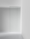 Glastäckad vägg med skjutdörr i minimalistisk, vit interiör.