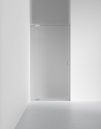 Glasdörr med minimalistisk design, genomskinlig och med metallhandtag, monterad i en vit vägg i ett modernt utrymme.