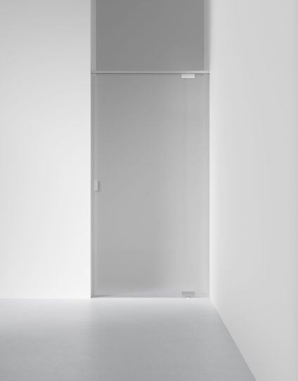 Frostat glasdörr i minimalistisk vit interiör, del av väggen och golvet synliga.