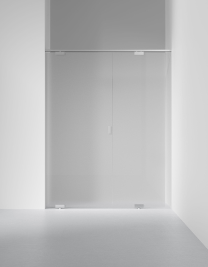Skjutbar glasdörr med minimalistisk design monterad på en metallstång, omgiven av vita väggar och ett ljusgrått golv.