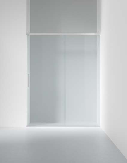 Glasdörr i en minimalistisk vit interiör med matta paneler och en vertikal handtagslist.