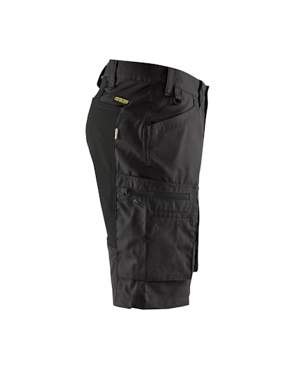 Svarta shorts med fickor och verktygshällor, set från sidan mot vit bakgrund.