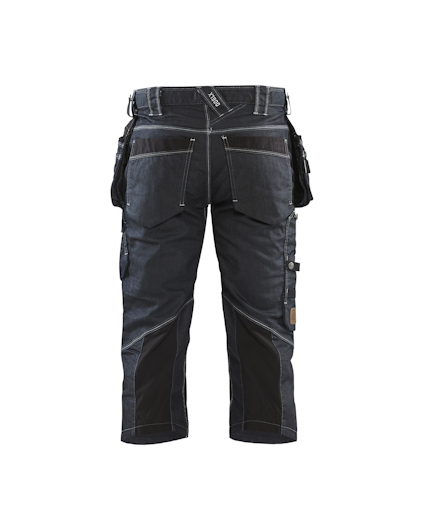 Arbetsbyxor i mörk denim med svarta förstärkningar och flera fickor, bakifrån.