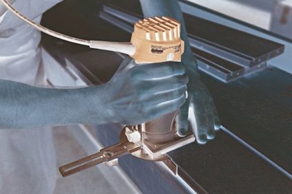 Person använder en handhållen fräs på en träskiva i en verkstad.