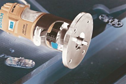 Handöverfräs på ett träbord med mässingsgångjärn och träspån runt omkring.