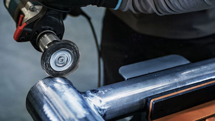 Borrmaskin med slipborste polerar en metallisk yta.